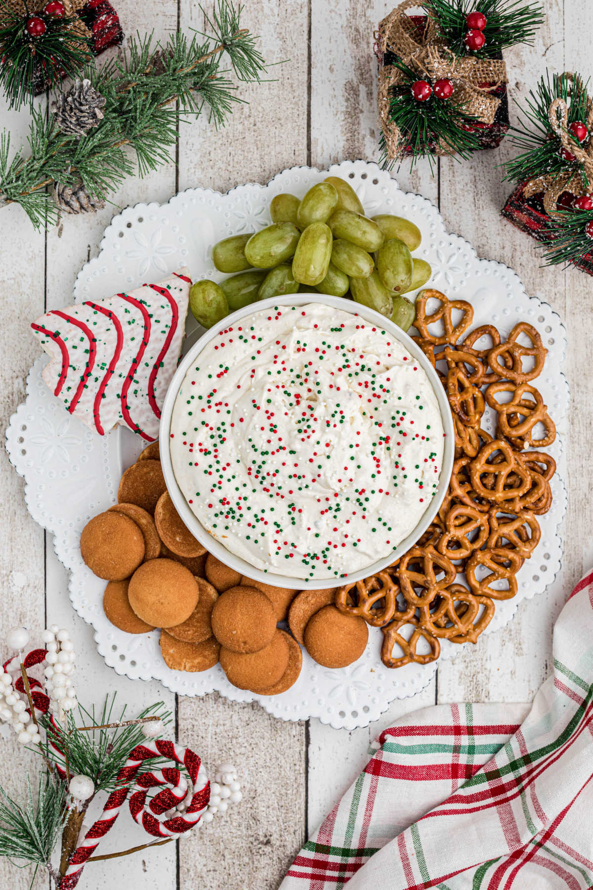 Overhead shot of a plate, with a bowl of Christmas Tree Dip, surrounded by cookies and fruit to dip into.