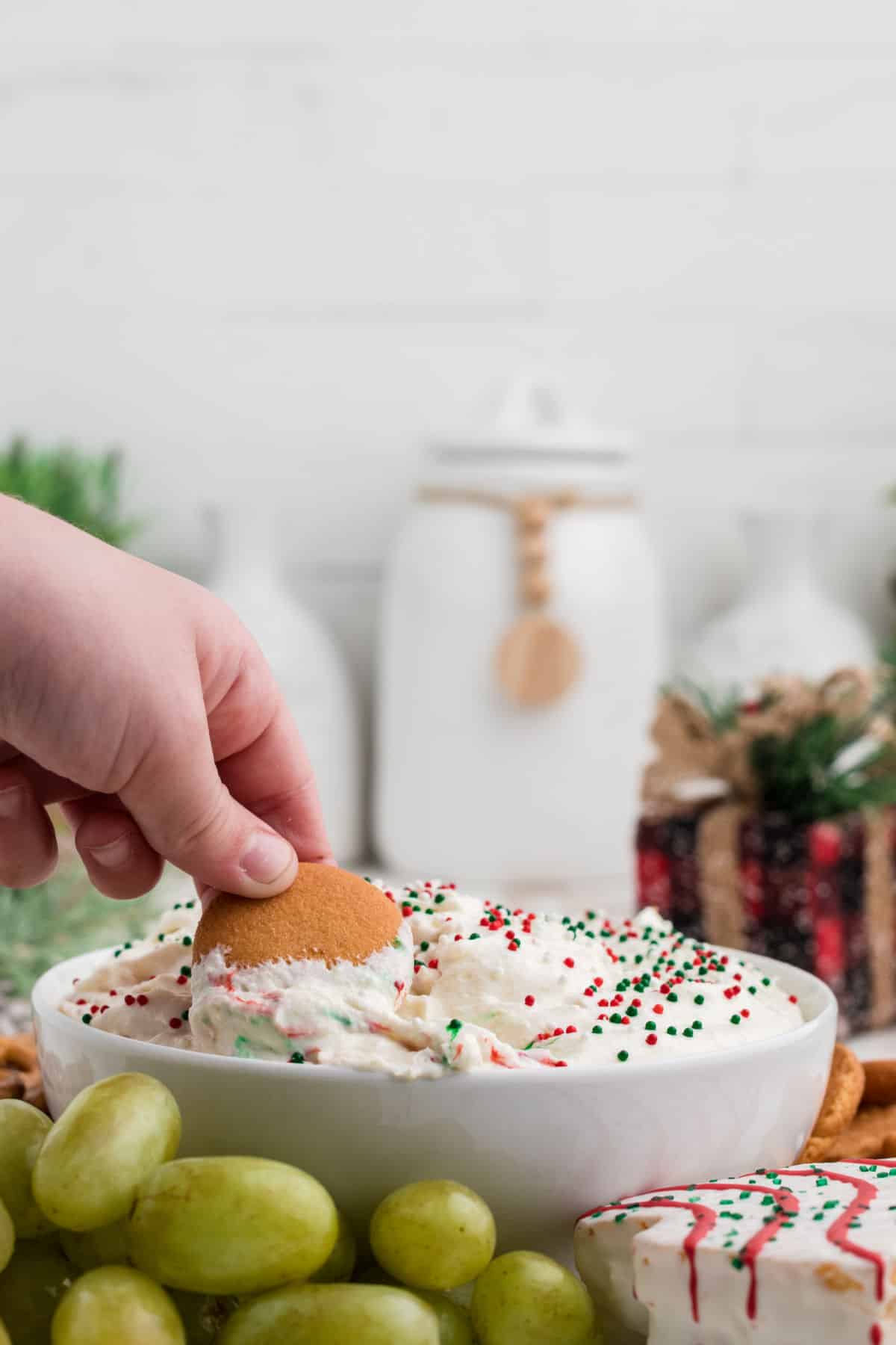 A child's hand dipping a cookie into Christmas Tree Dip.