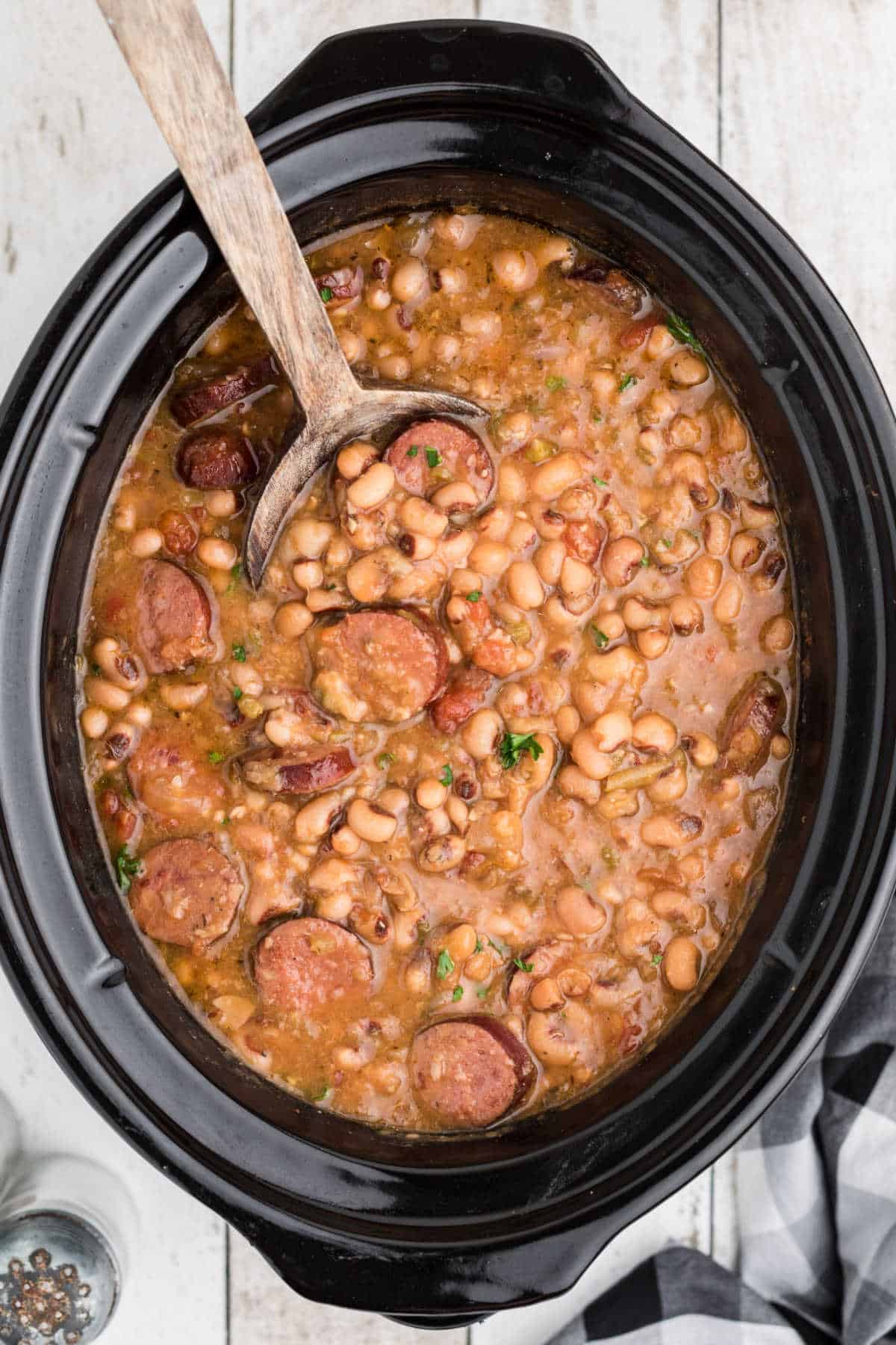 Close up shot cropped square, of a crock pot hoppin john with a spoon diggin in.