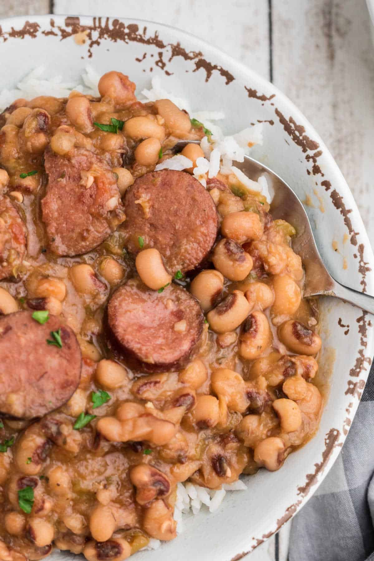 Close up shot cropped square, of a crock pot hoppin john with a spoon diggin in.