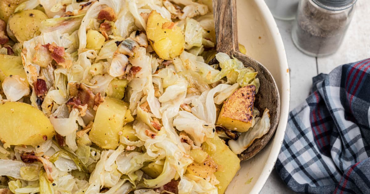 Close up image of a skillet full of fried cabbage and potatoes.