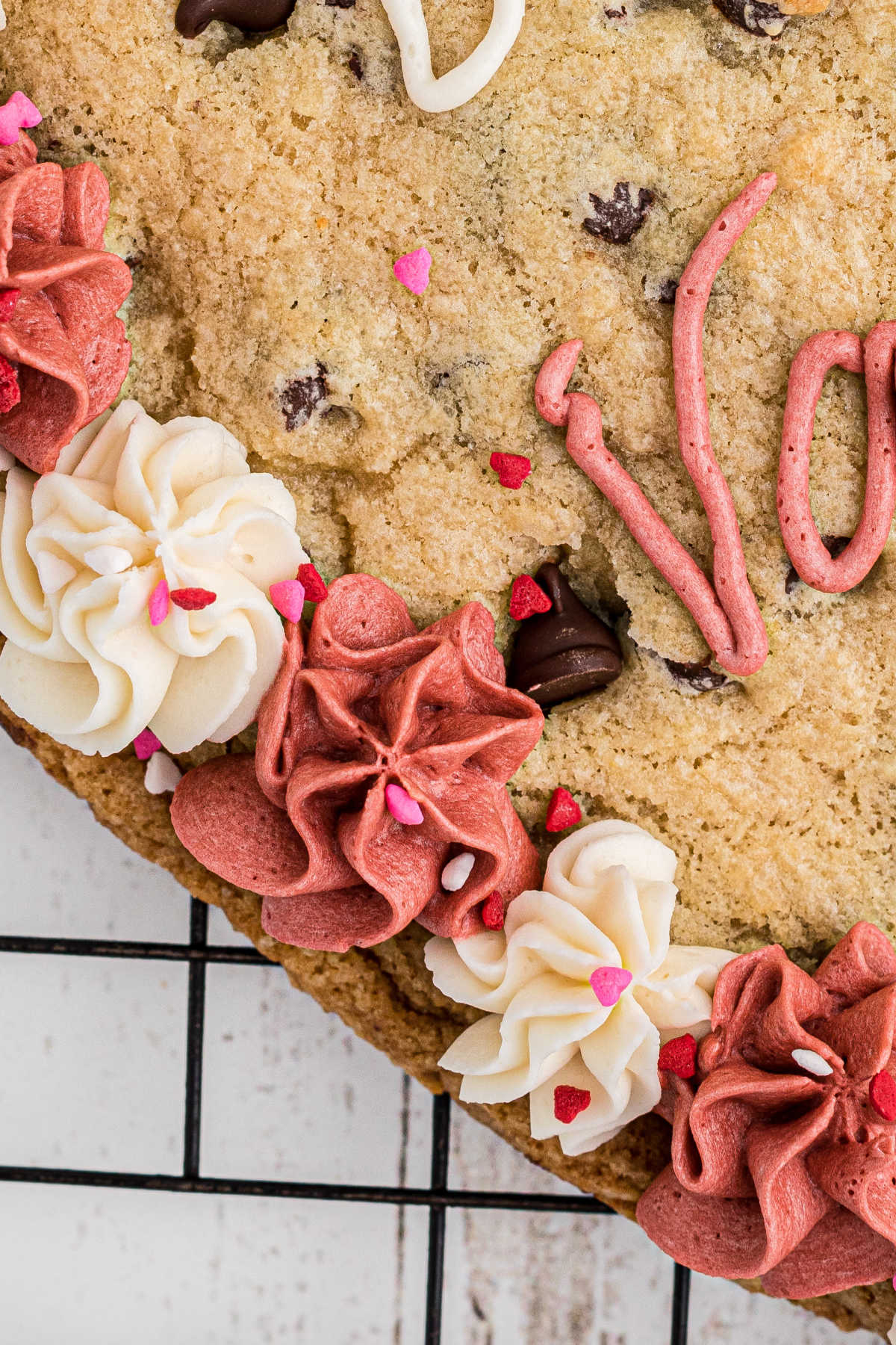 Close up of a side of a giant valentines cookie, of the white and pink frosting.