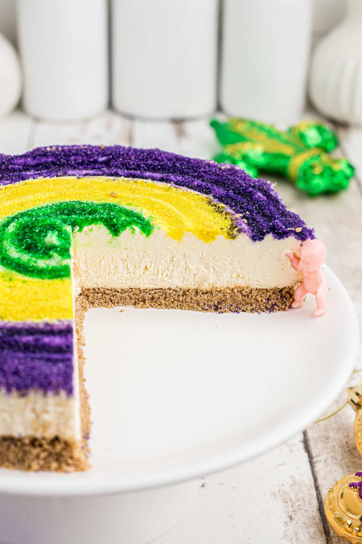 A mardi gras cheesecake with slices missing.