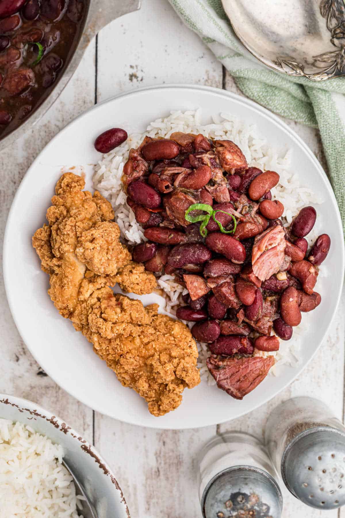 A dished up plate of fried chicken and red beans and rice with ham hocks.