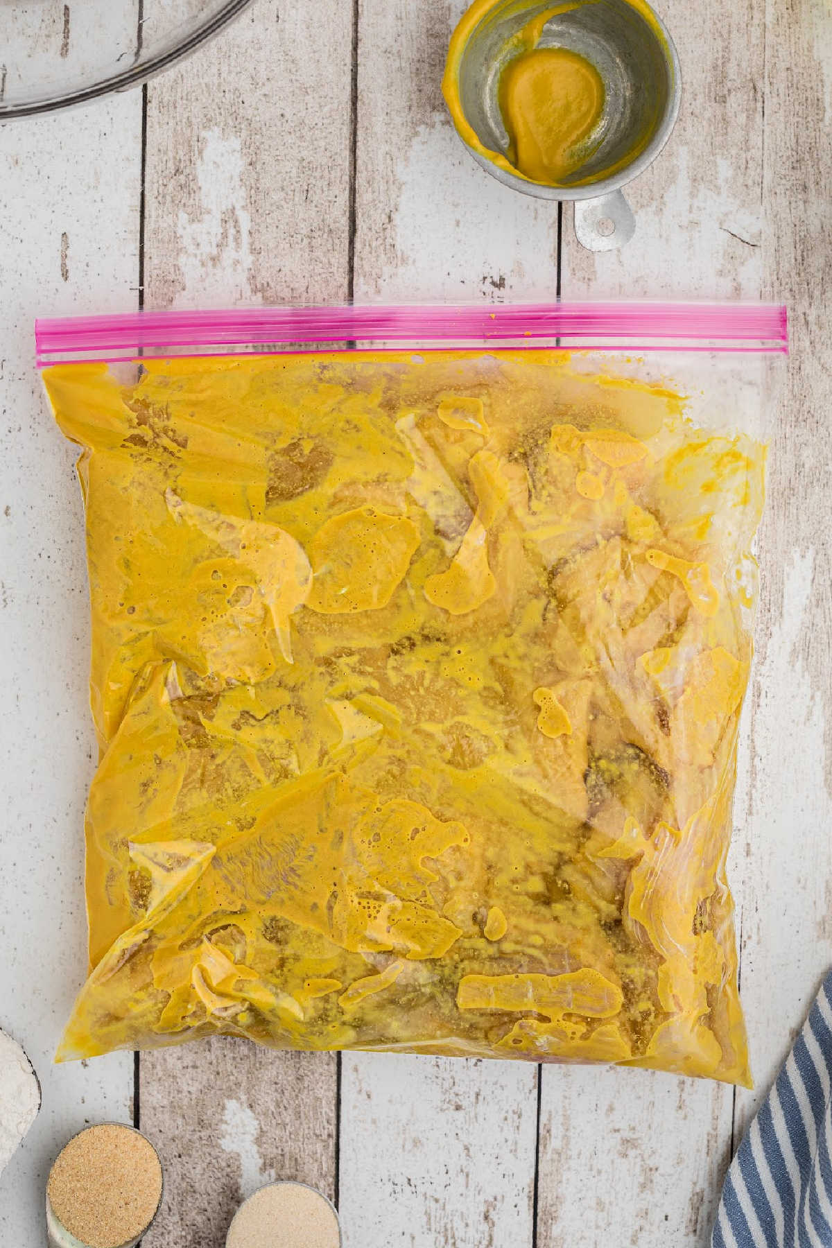 A resealable bag filled with catfish fillets and mustard.