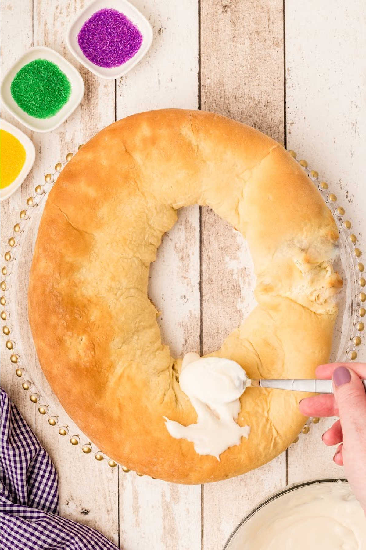 Glaze being spooned onto a cooked King Cake.