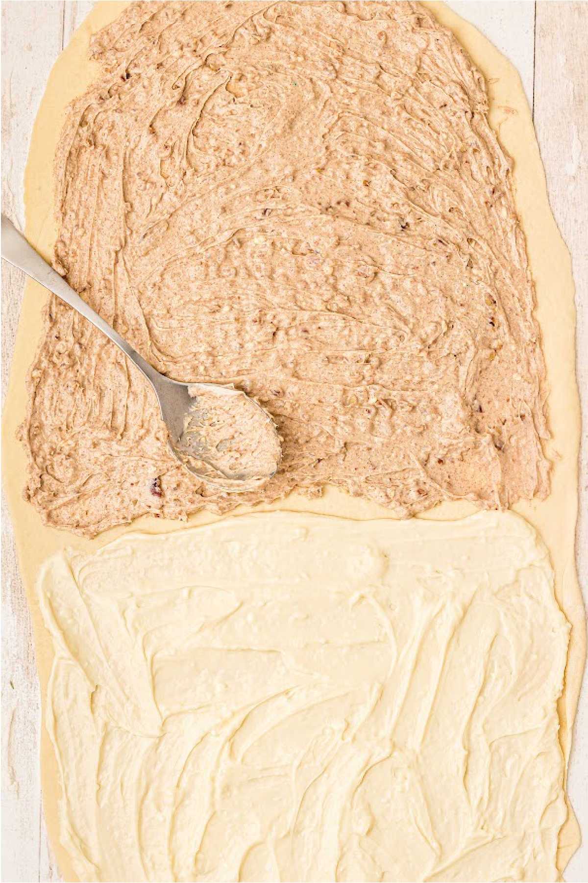 Rolled out dough with a filling being spooned over it.