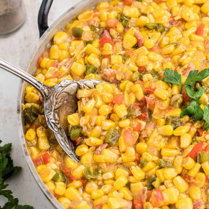 Close up of some cajun corn maque choux with a big spoon digging in.