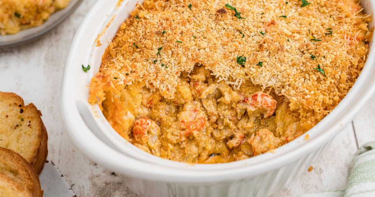 A baking dish with crawfish au gratin with a scoop missing.