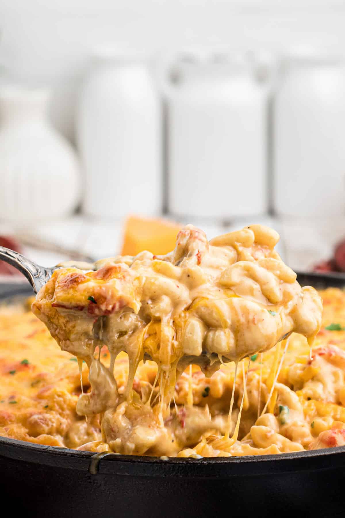 Close up side shot of a spoon lifting out some cheesy crawfish mac and cheese.