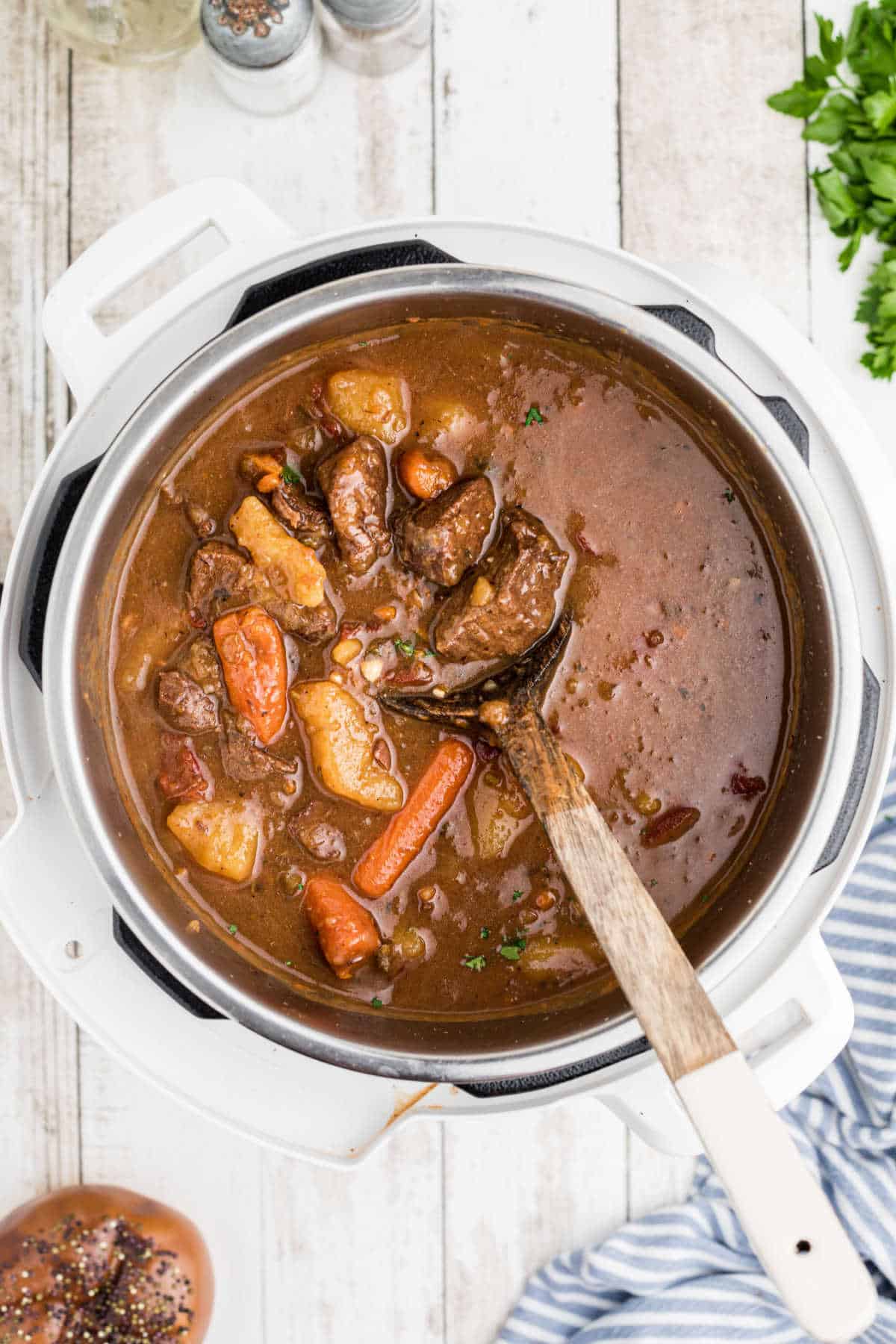 Overhead shot of an open instant pot with venison stew and a wooden spoon.