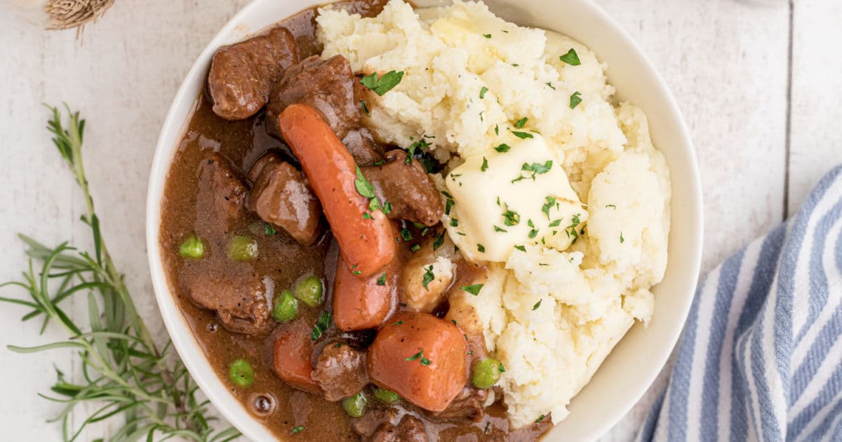 An overhead close up shot of a bowl of Irish stew with mashed potatoes.