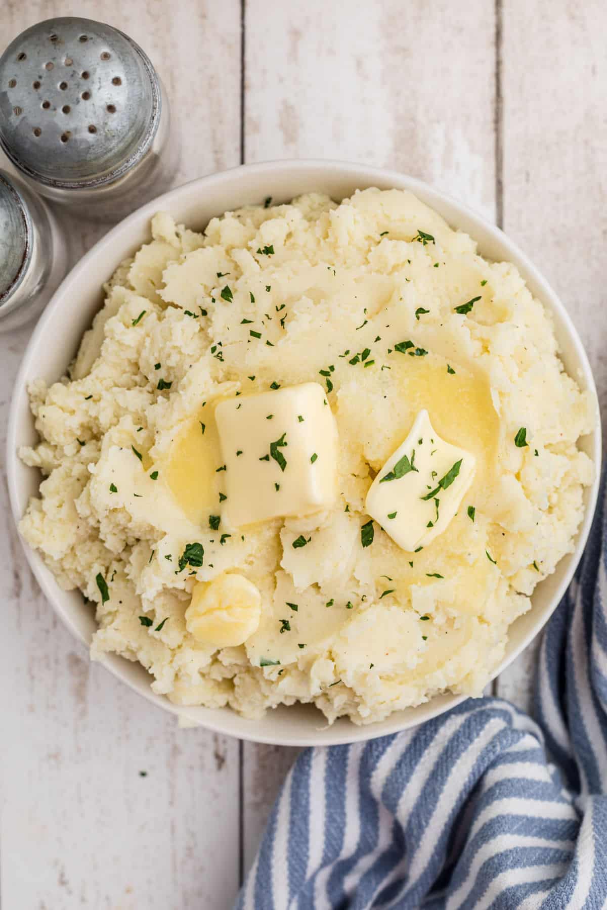 Overhead shot of a full bowl of mashed potatoes with butter melting on top.