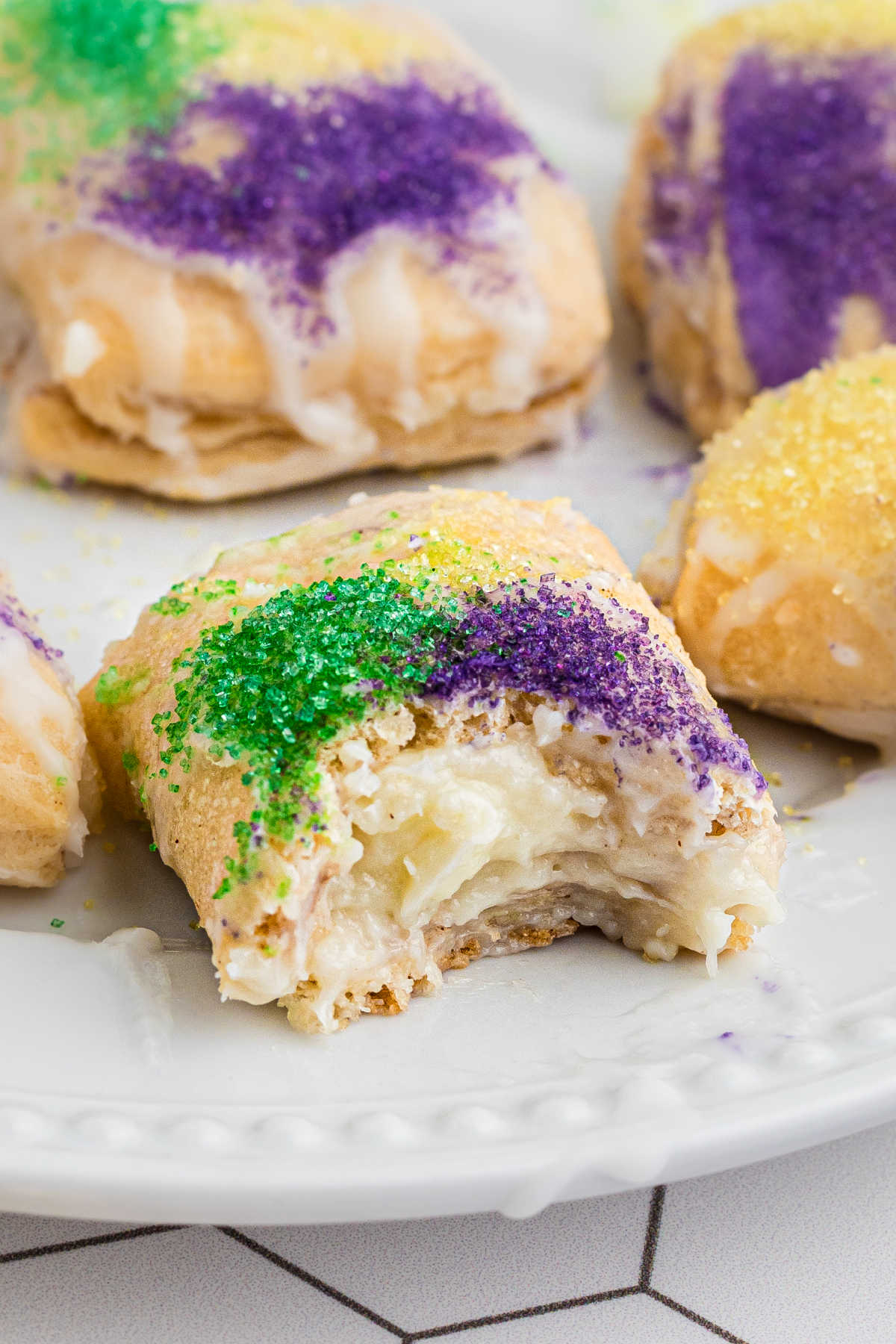 Close up of a king cake bite with a bite taken out.