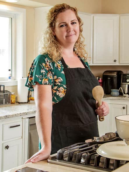 Picture of Melanie Cagle standing with a wooden spoon in her kitchen.