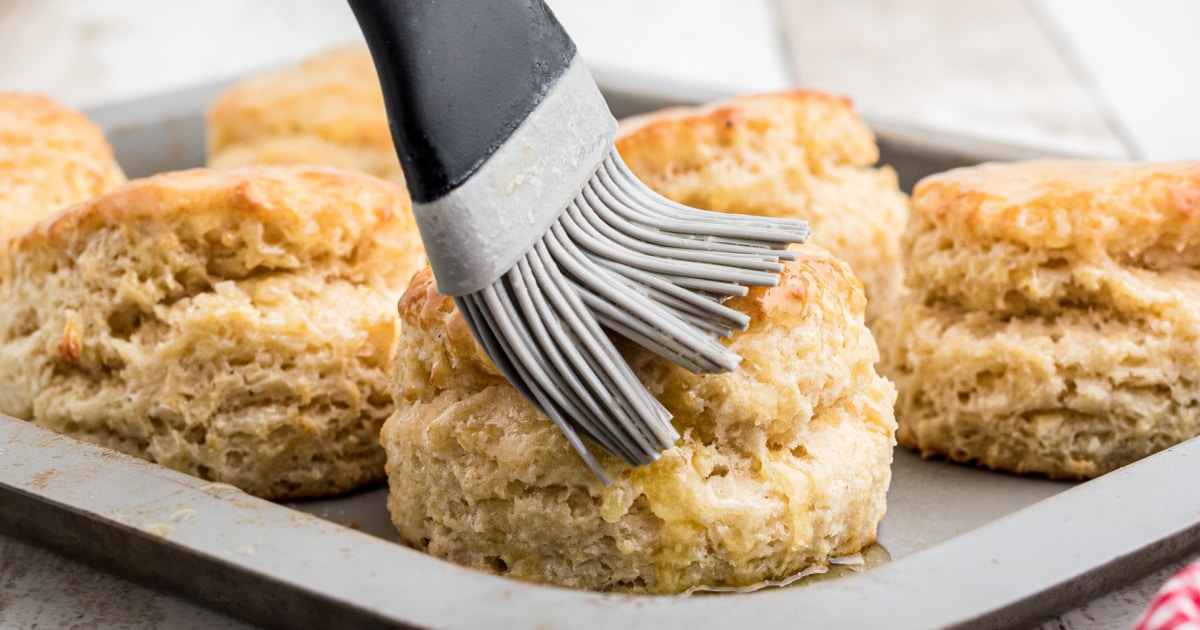 A fluffy southern biscuit being brushed with butter.