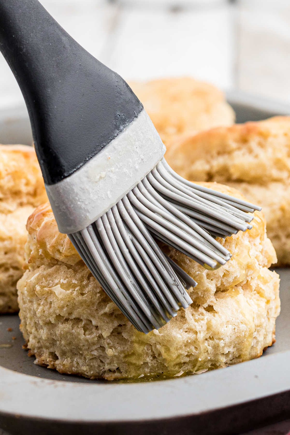 A pastry brush brushing some old fashioned southern biscuits.