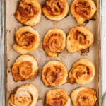 A baking sheet full of puff pastry pizza pinwheels, with text overlay for pinterest.