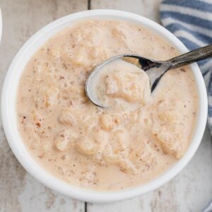 Rice pudding with evaporated milk in a bowl with a spoon digging in.