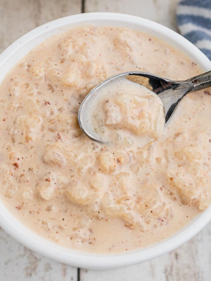 Rice pudding with evaporated milk in a bowl with a spoon digging in.