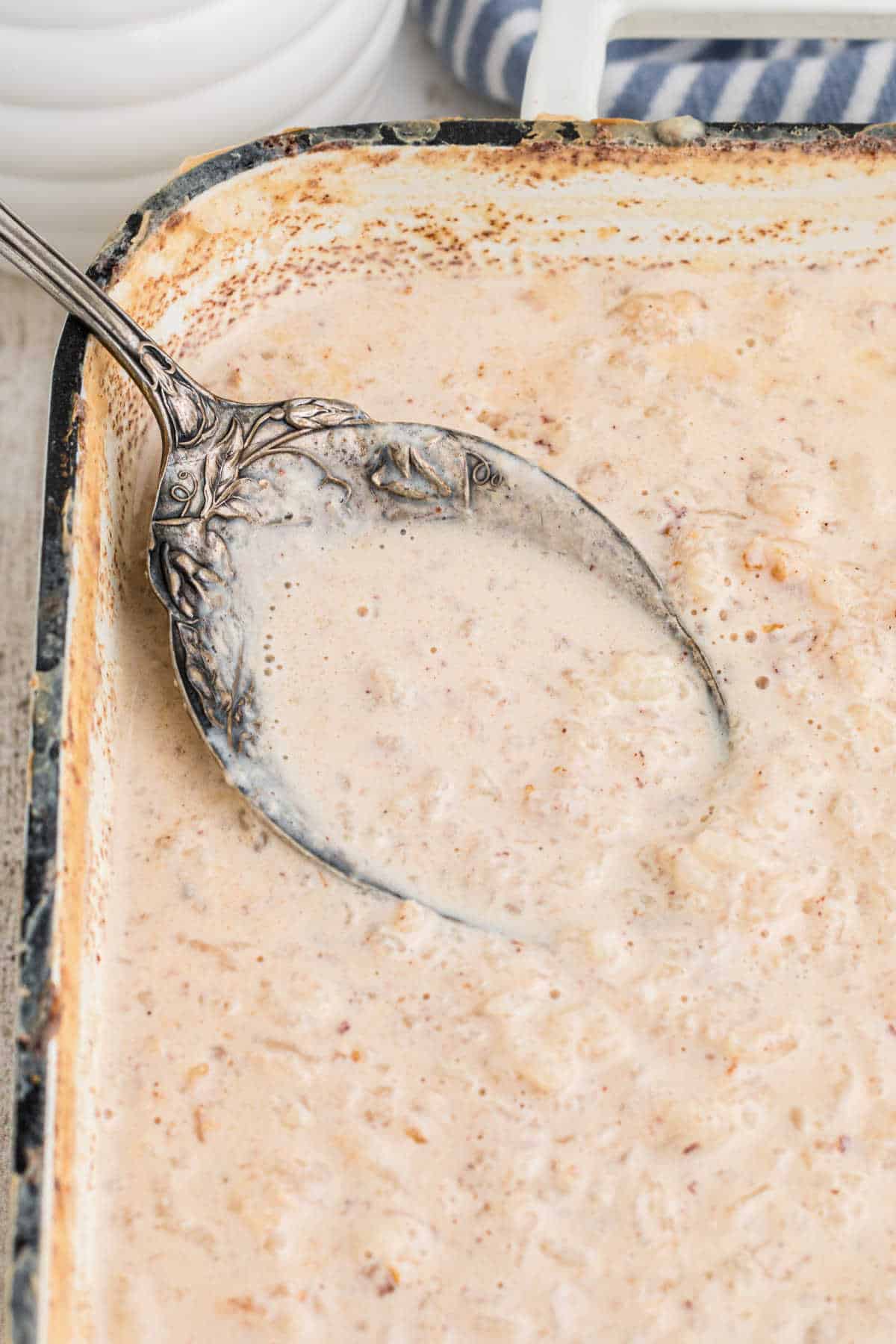 Large pan of rice pudding with evaporated milk, with a spoon digging in.