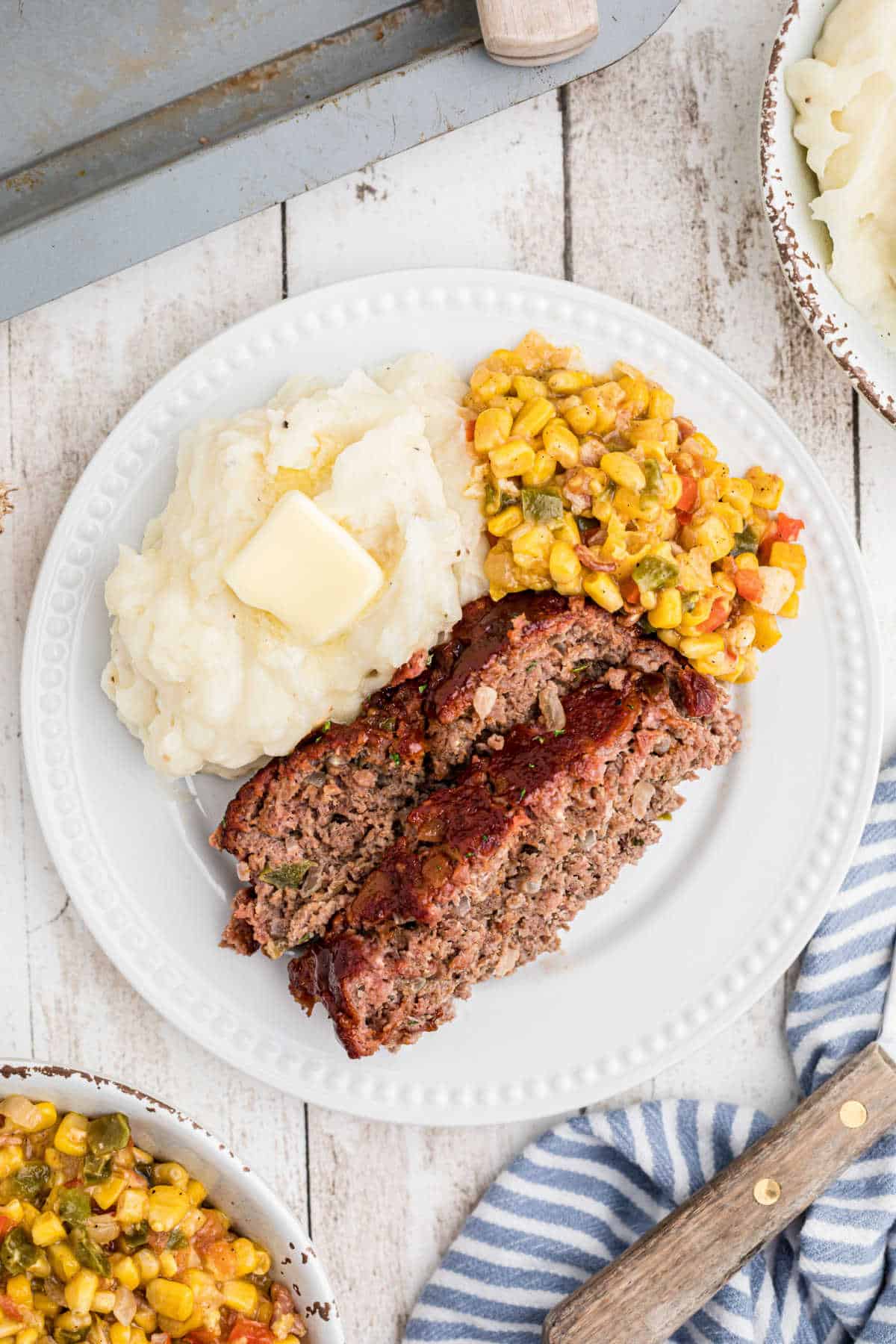 Overhead shot of a plate of smoked meatloaf dished out with some mashed potatoes and corn.