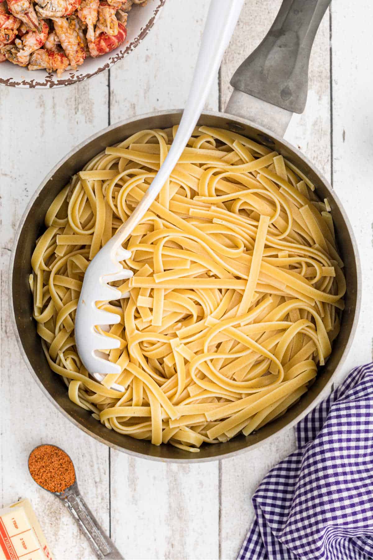 Cooked Fettuccine in a pot with a pasta spoon.