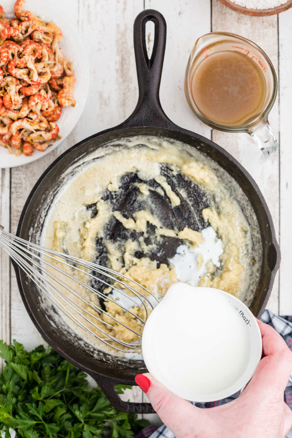 Milk being slowly poured into a black skillet.