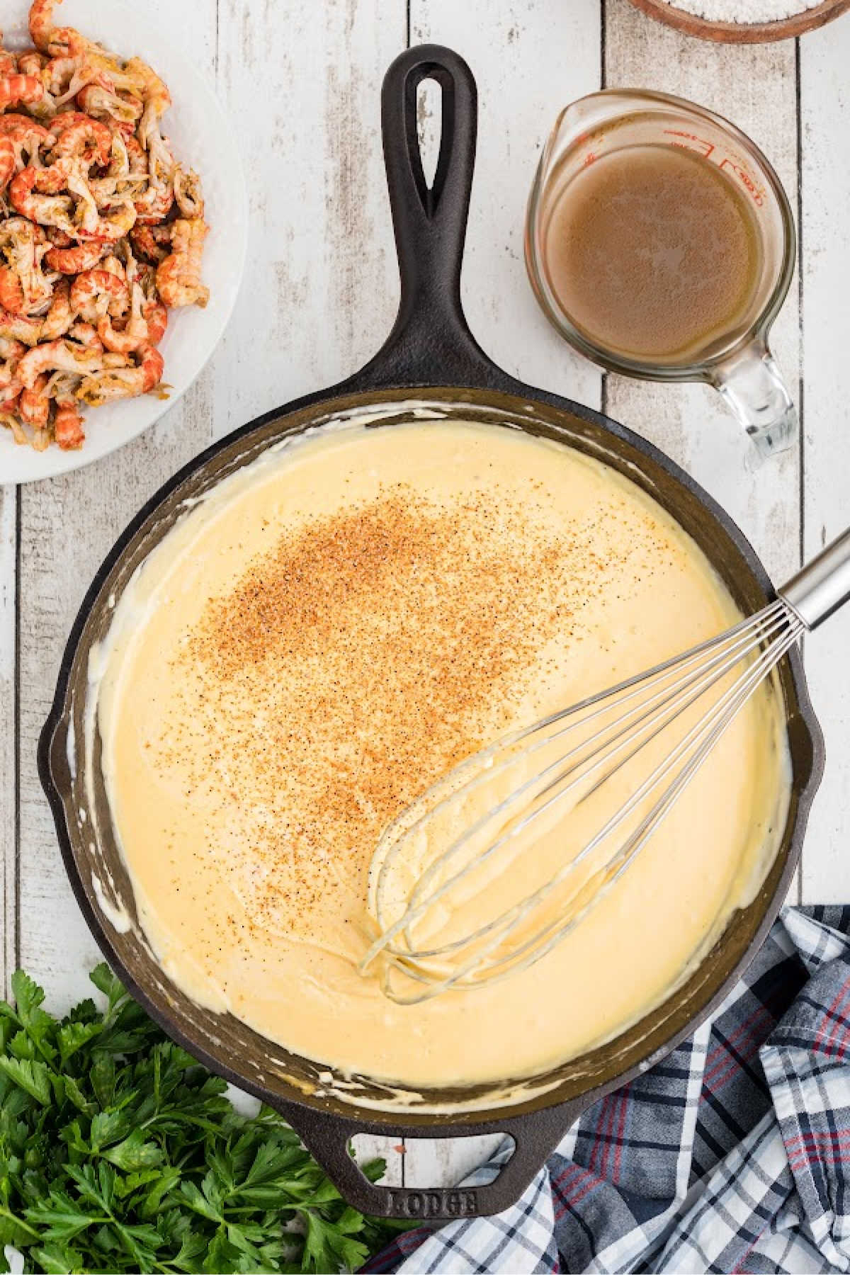 Seasoning being added to a black skillet full of cheese sauce.