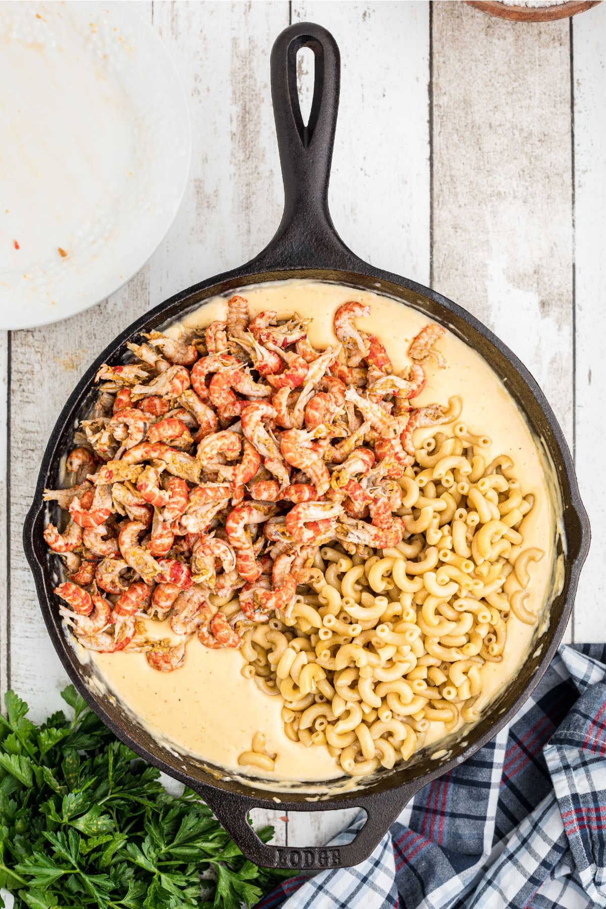 Noodles and crawfish tails added to a skillet with cheese sauce.