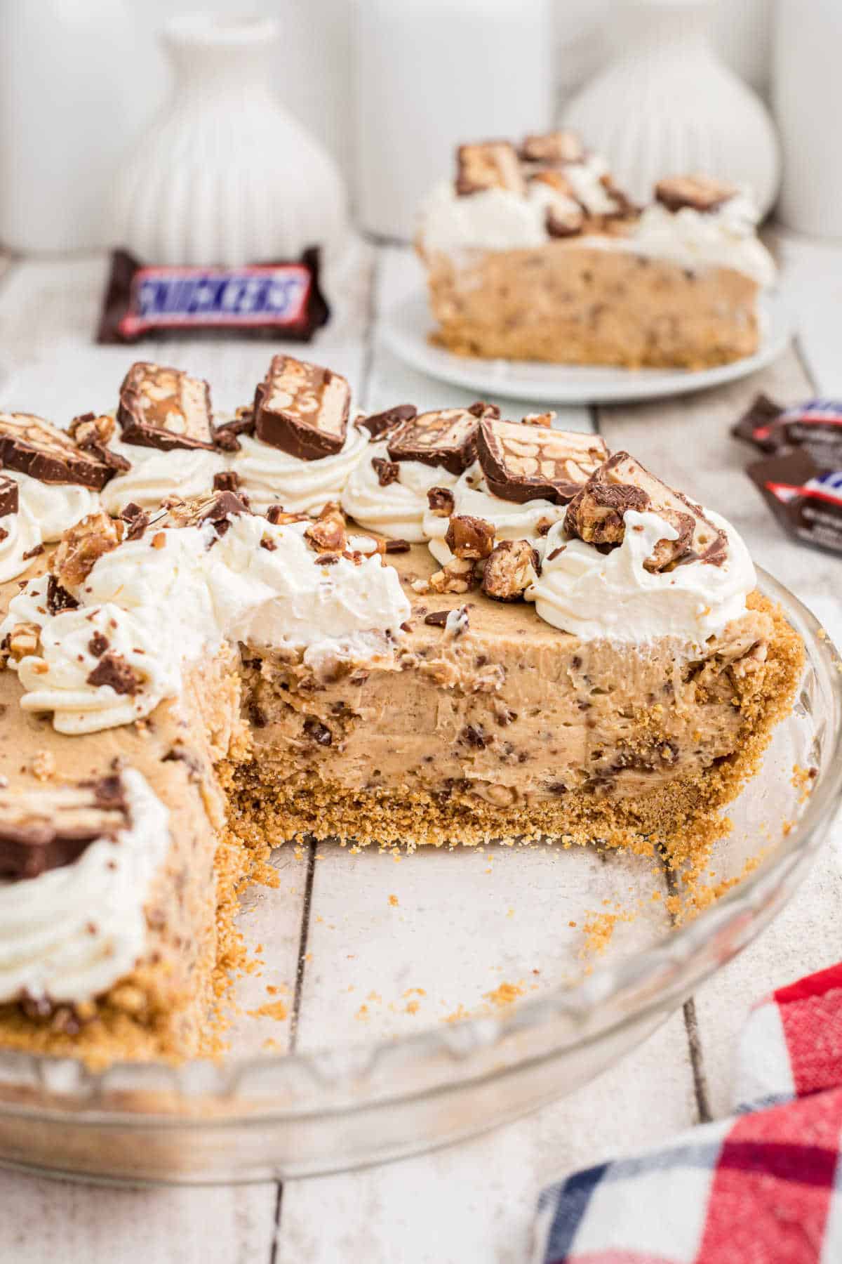 Close up of a snickers bar pie with a slice removed.