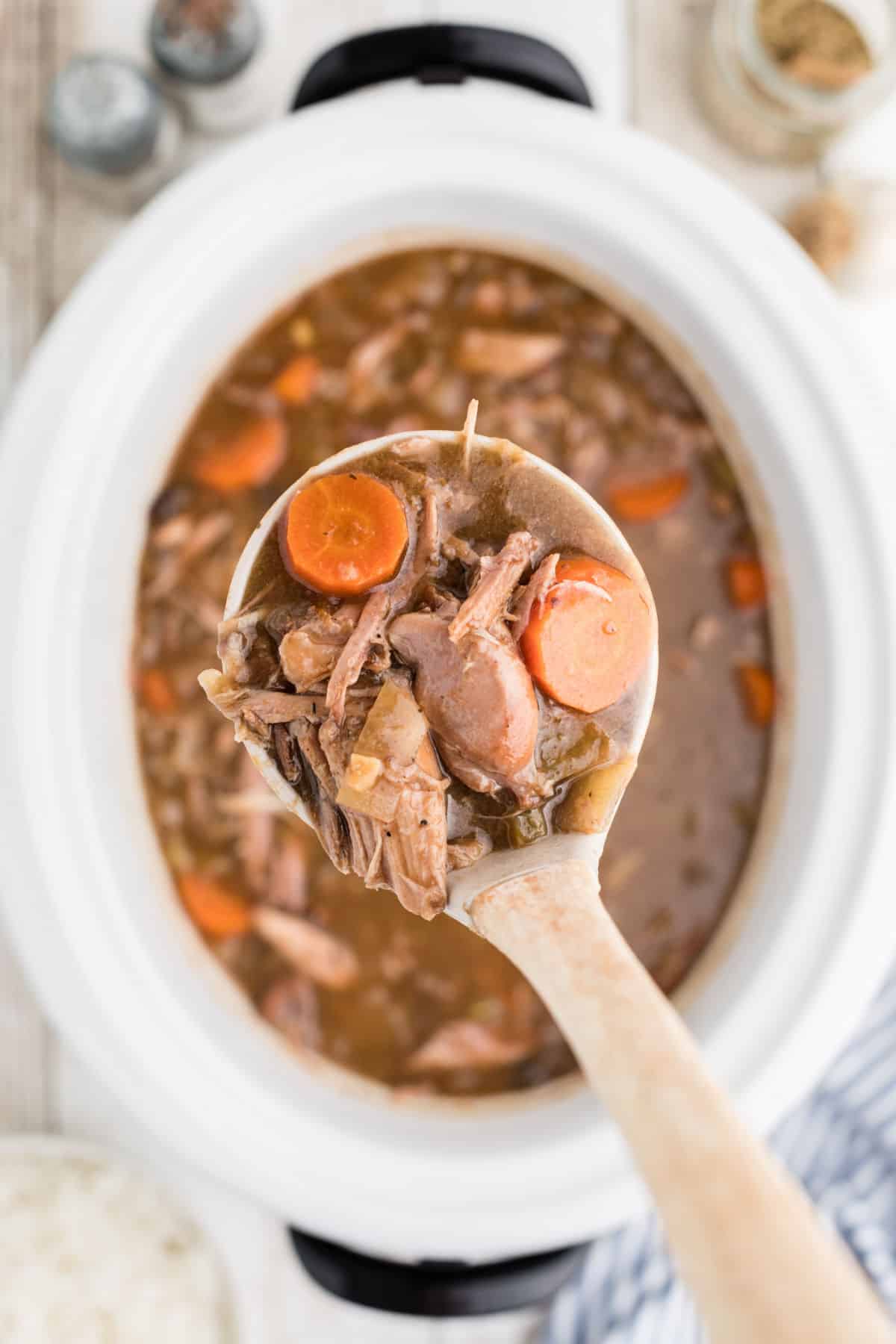 A slow cooker rabbit stew with a ladle pulling some out.
