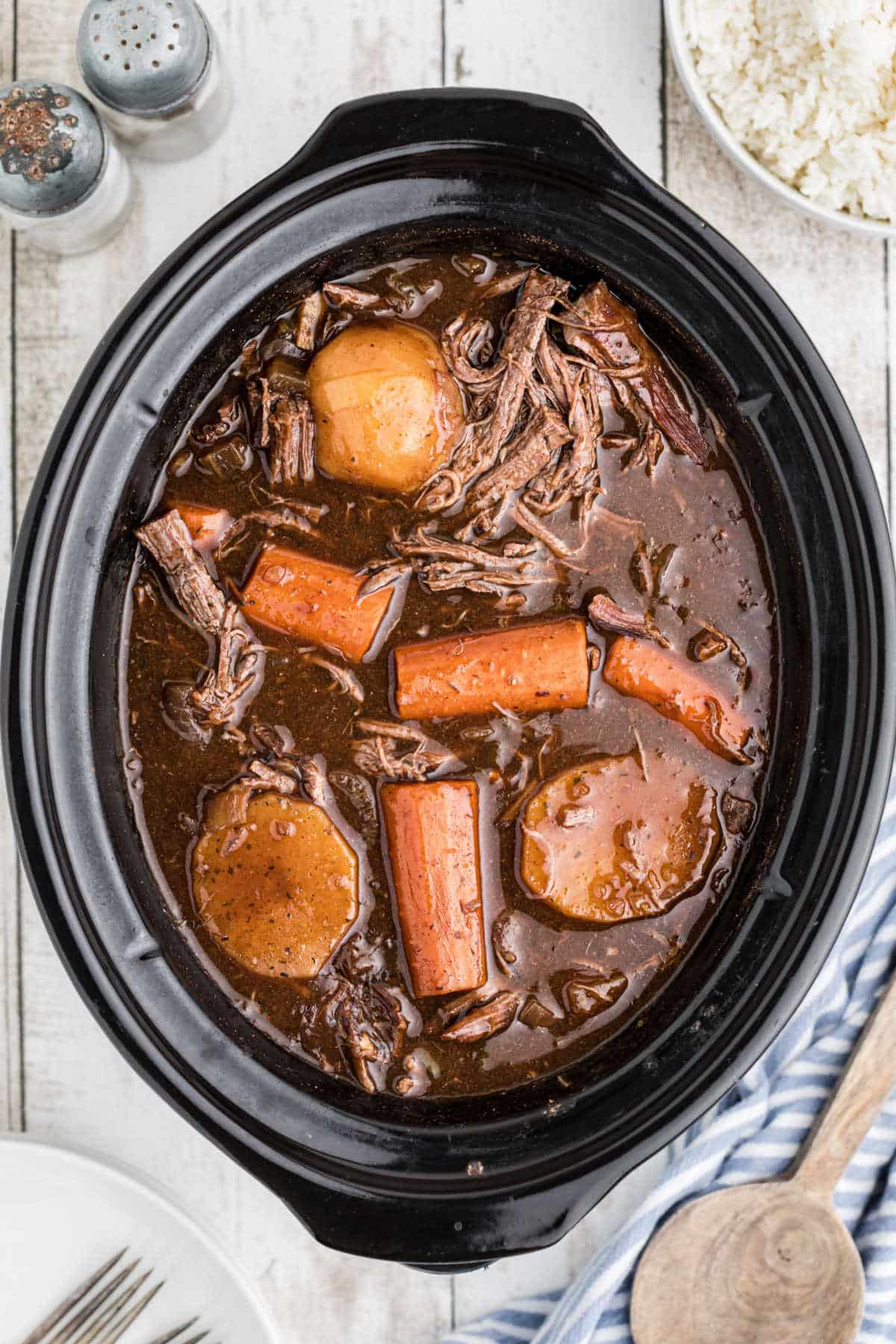 Overhead shot of a slow cooker full of venison roast with red wine and carrots and potatoes.