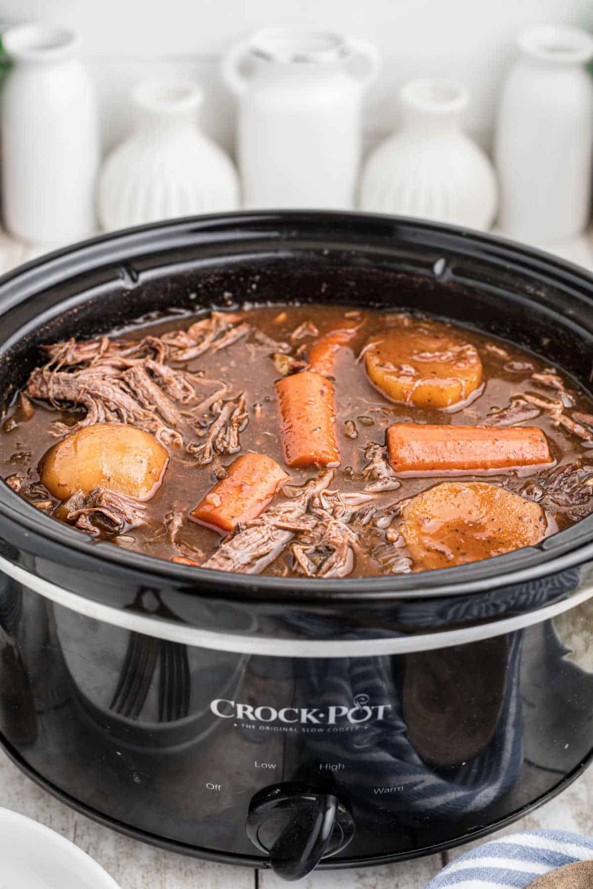 Front view of a slow cooker with venison roast with red wine.