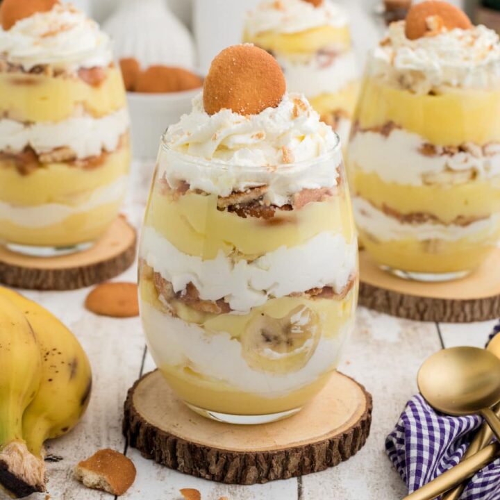 Some banana pudding cups sitting on top of wooden coasters.