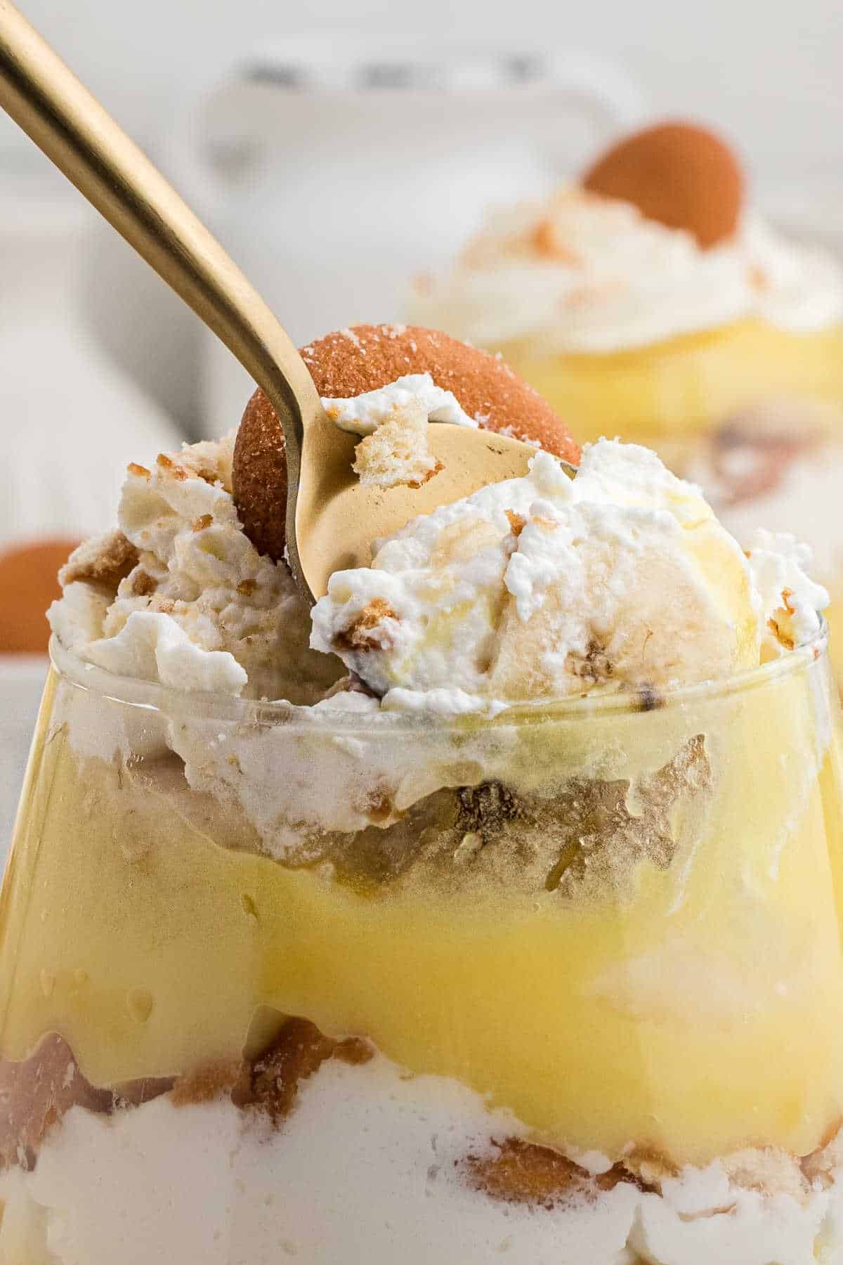Close up of a banana pudding cup with a spoon taking some out.