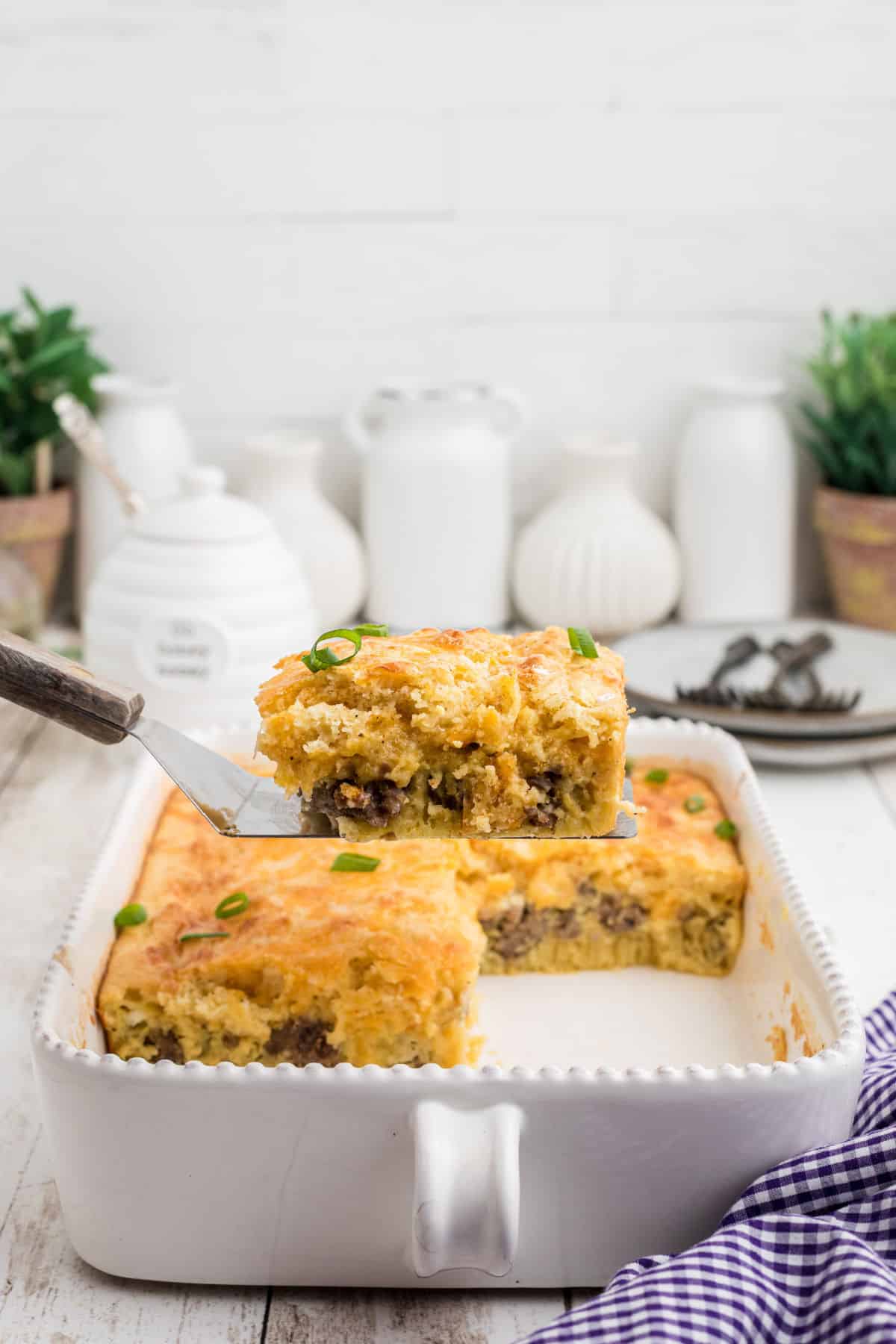 A slice of bisquick breakfast bake being lifted out of a casserole dish.