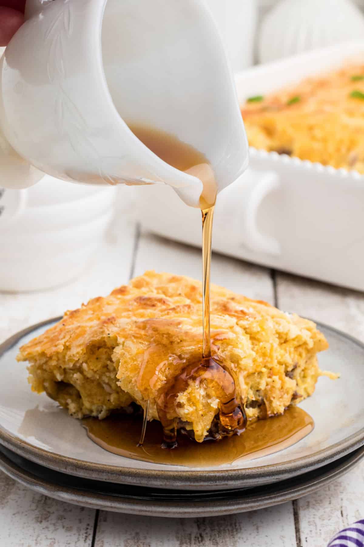 A piece of bisquick breakfast casserole having syrup poured over.