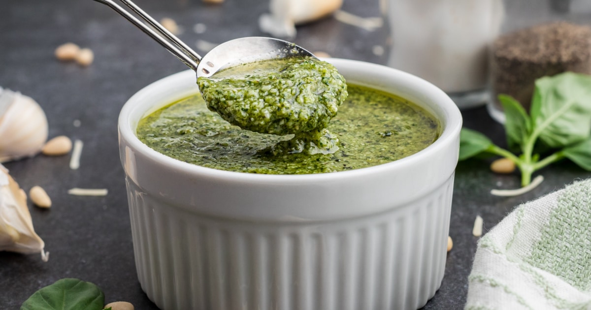 Close up of a bowl of pesto dressing with a spoon digging in.