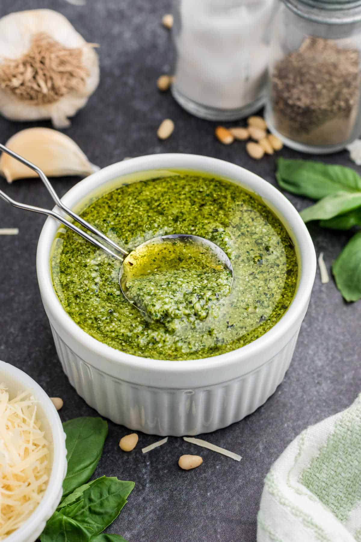 A small bowl of a pesto dressing with a spoon digging in.