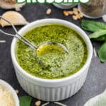 Pesto dressing in a bowl with a spoon digging in with text overlay for pinterest.
