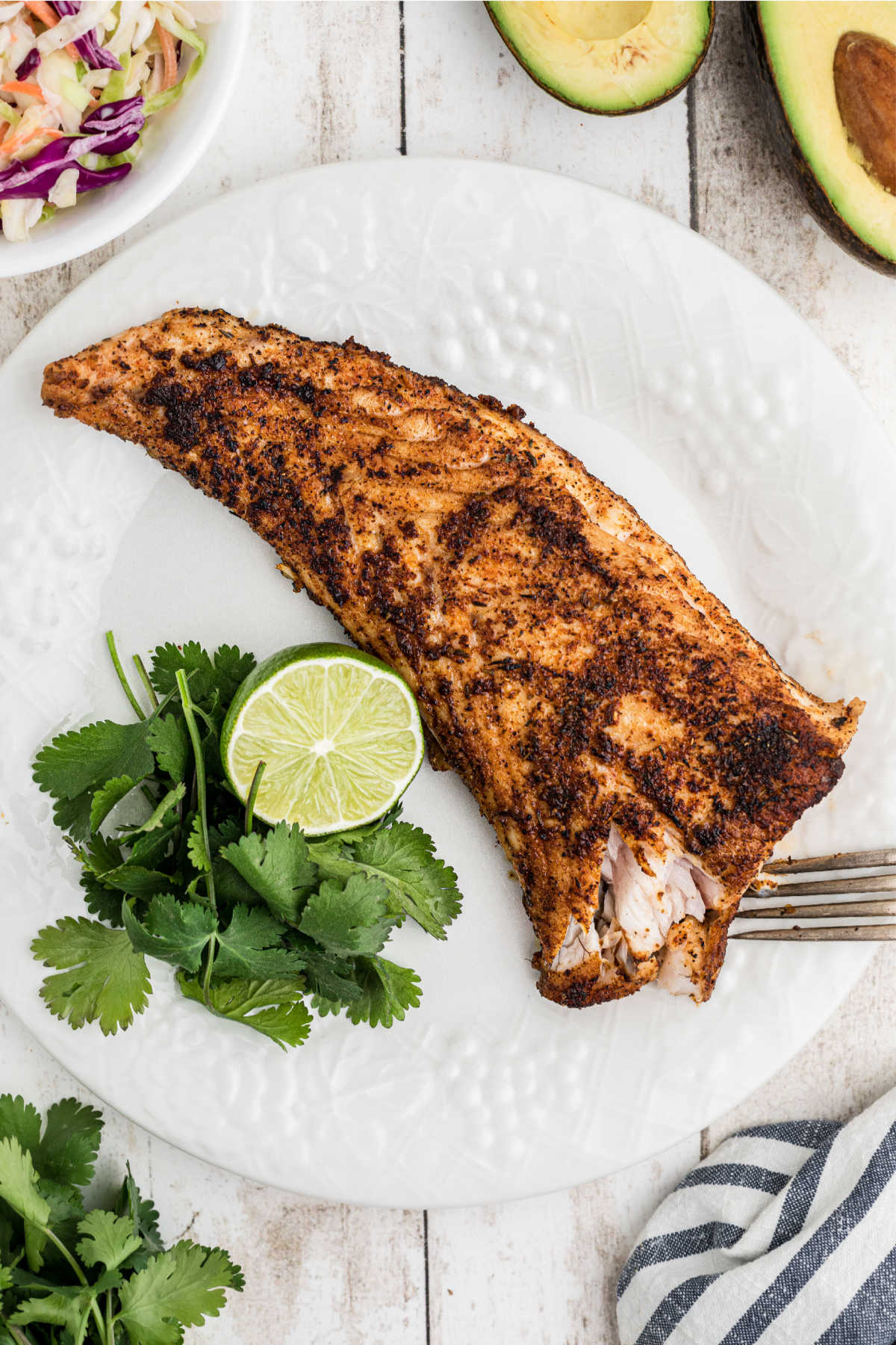 A redfish fillet being flaked apart with a fork.