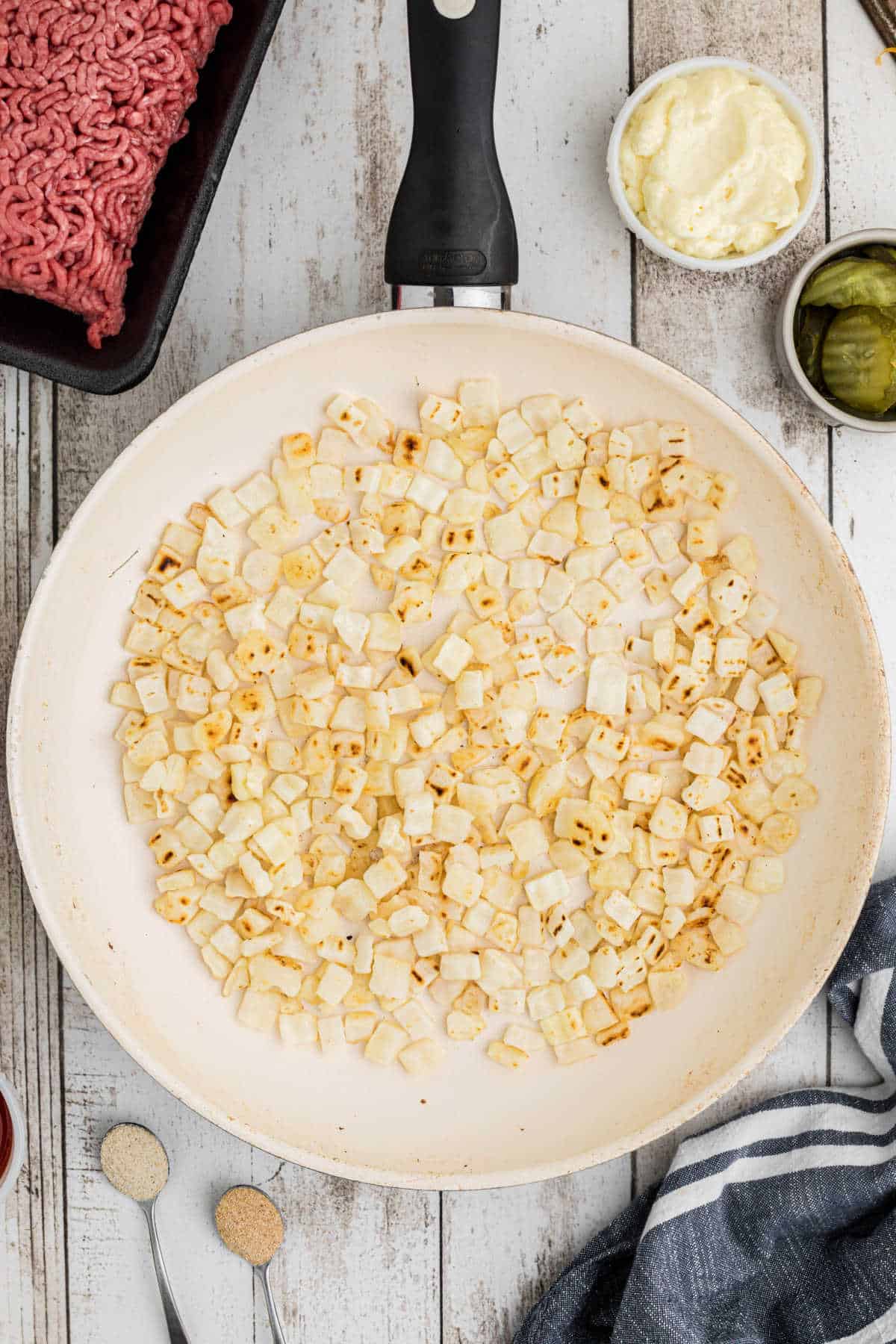 Overhead shot of a large skillet filled with onions, cooking.