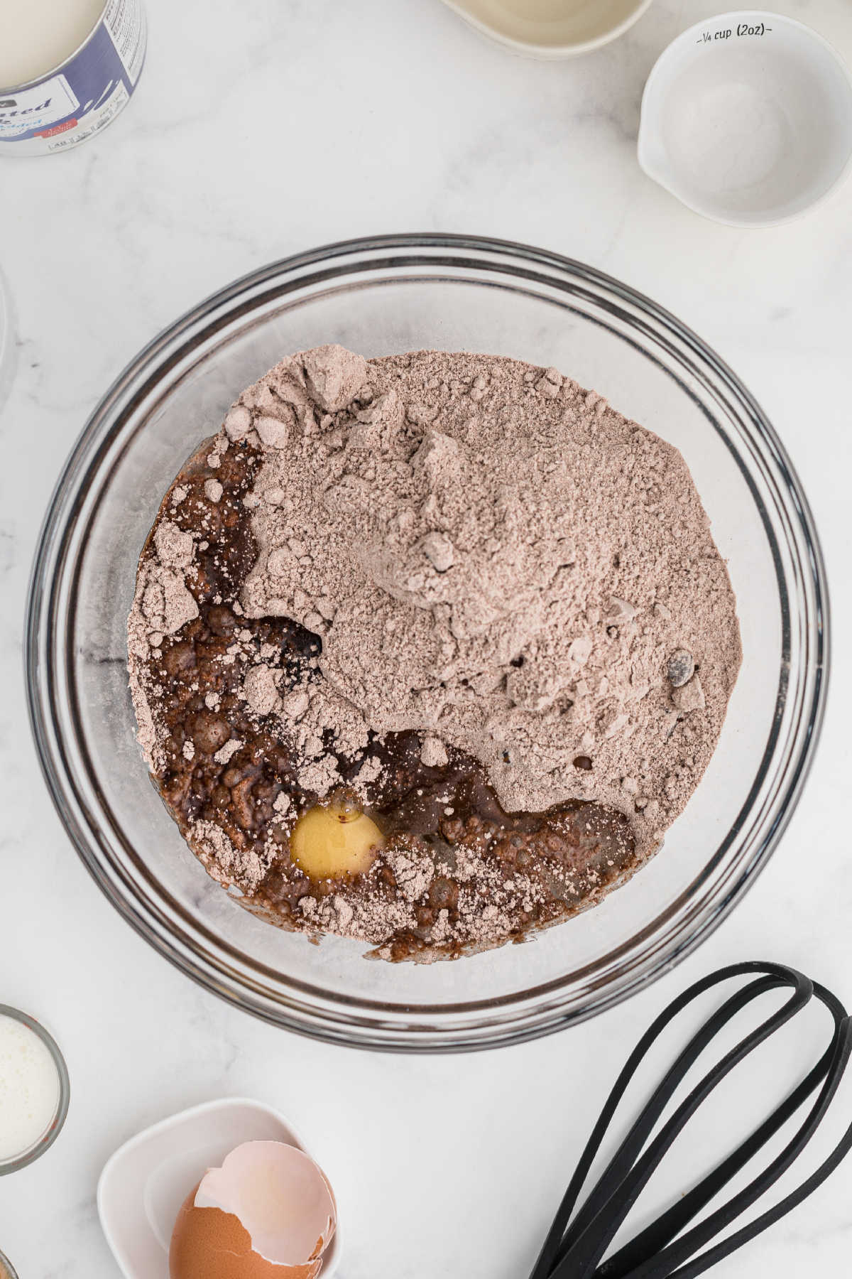 Brownie mix in a mixing bowl with eggs and oil, ready to be mixed.