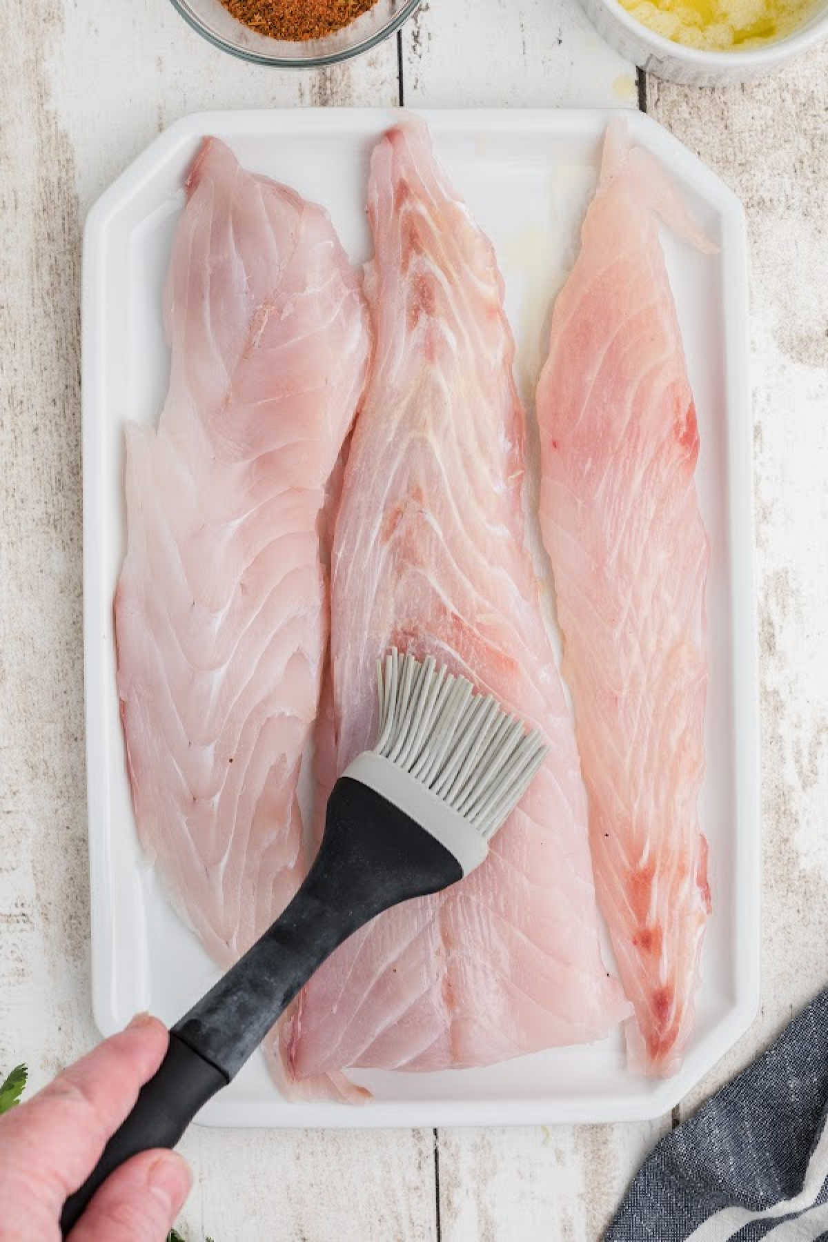 Butter being brushed onto some redfish fillets.