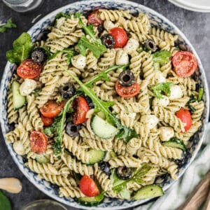 Overhead shot of a bowl of summer pesto pasta salad, cropped square.