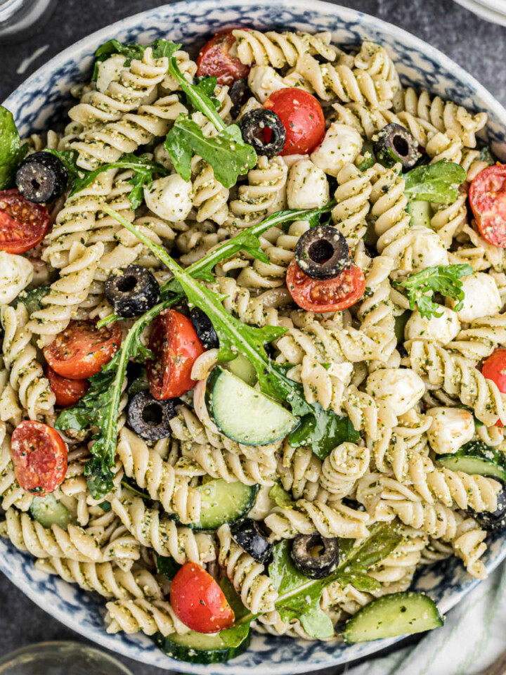 Overhead shot of a bowl of summer pesto pasta salad, cropped square.