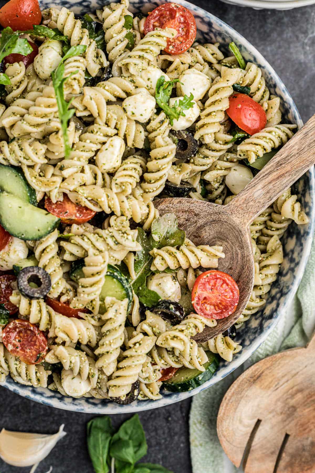 Overhead close up shot of a bowl of summer pesto pasta salad with a spoon hanging out in there.