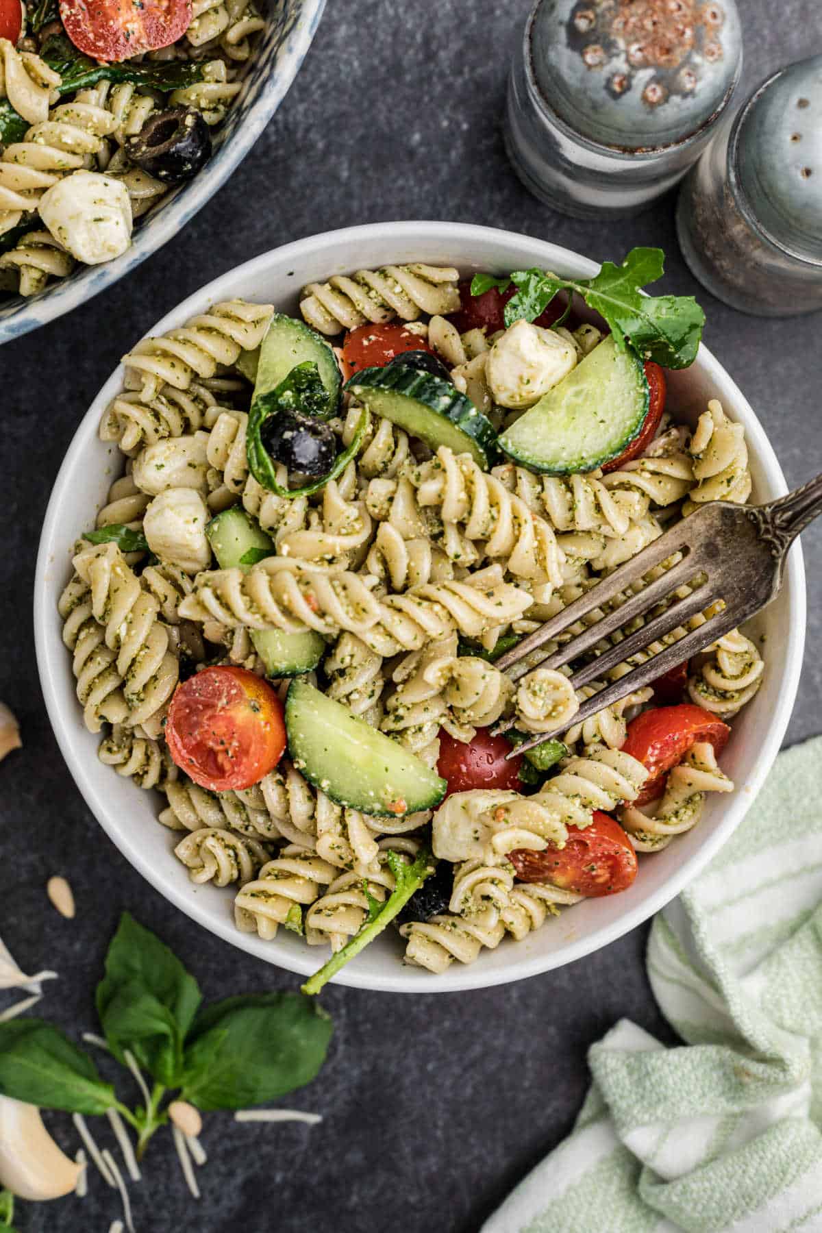 A dished up bowl of summer pesto pasta salad with a fork digging in.