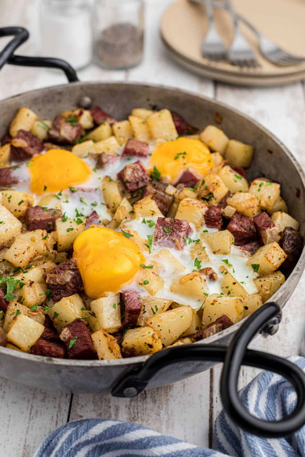 Side view of a pan with irish corned beef hash with some eggs on top.